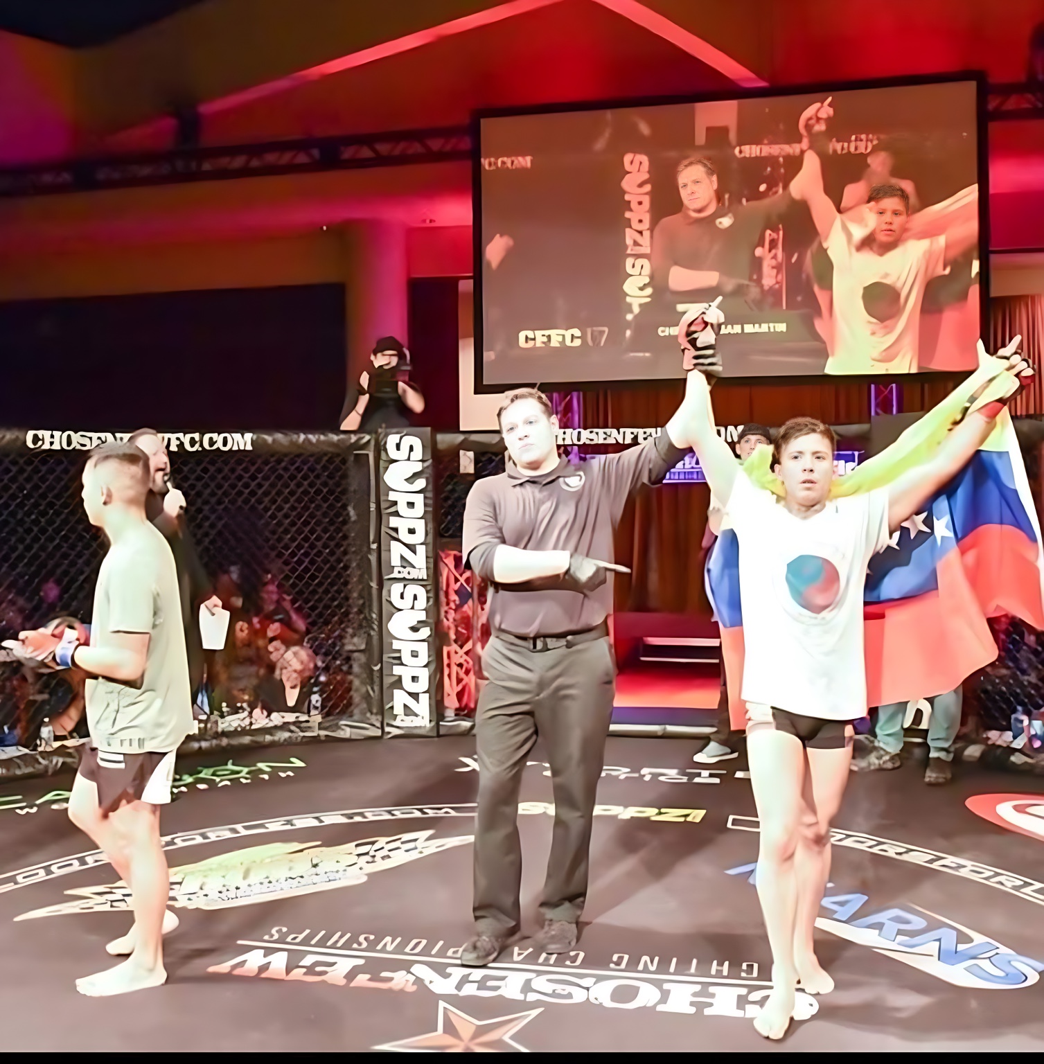 Cris having his hand raised after a fight while holding the Venezuelan flag